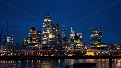 Cityscape of cinematic London downtown at evening, United Kingdom. Skyscrapers in City district, Thames River with the Millennium Bridge over it, a lot of illumination - Starpik Stock