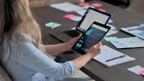Video - Woman working with a tablet pc at the office, business charts, slow motion