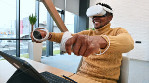 A black man exploring virtual reality using VR glasses and controllers in an office. Slow motion - Starpik
