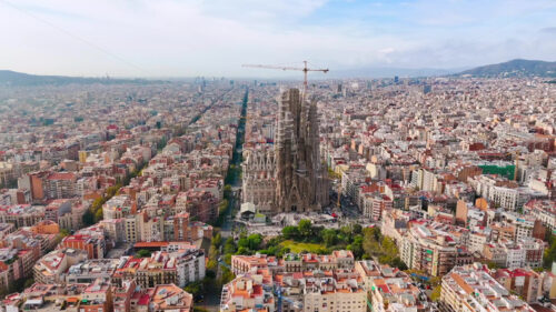 Aerial drone view of Sagrada Familia in city downtown. Famous residential districts around, greenery - Starpik