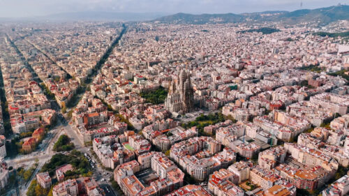 Aerial drone view of Sagrada Familia in city downtown. Famous residential districts around, greenery - Starpik