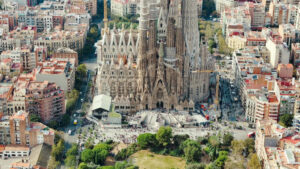 Aerial drone view of Sagrada Familia in city downtown. People and residential districts around, greenery - Starpik