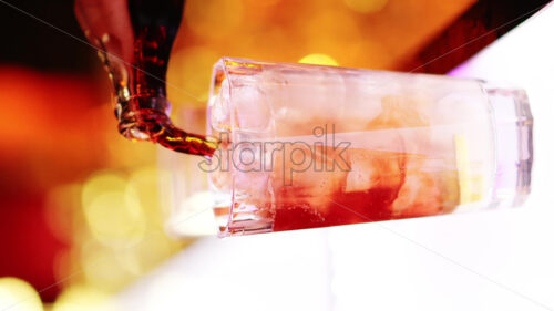 Barman pouring cola soda into an ice glass at the bar at night with red neon lights, slow motion vertical screen - Starpik