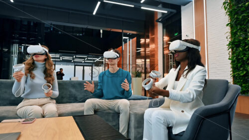 Business conference in VR in an office. Multiracial group of people using VR glasses and controllers, virtual reality - Starpik Stock