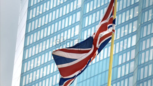 Close view of flag of the United Kingdom with skyscraper on the background London downtown. Slow motion - Starpik