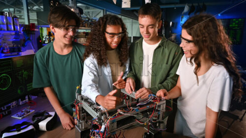 Group of young people doing experiments in robotics in a laboratory. Robot on the table - Starpik