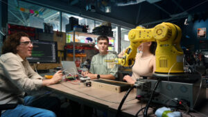 Group of young people doing experiments in robotics in a laboratory. Robots and tools on the table - Starpik