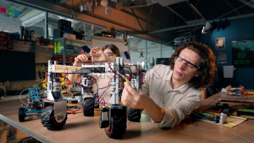 Group of young people doing experiments in robotics in a laboratory. Robots and tools on the table - Starpik