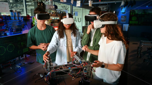 Group of young people in VR glasses discussing and doing experiments in robotics in a laboratory. Robot on the table - Starpik