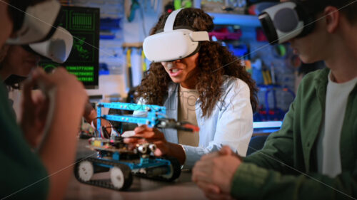 Group of young people in VR glasses doing experiments in robotics in a laboratory. Robot on the table, virtual reality - Starpik Stock