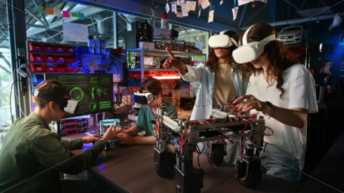 Group of young people in VR glasses doing experiments in robotics in a laboratory. Robots on the table - Starpik