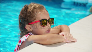 Little girl with red sunglasses resting at the pool - Starpik