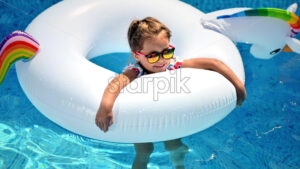 Little smiling girl swimming in the pool in a rubber ring. Slow motion - Starpik