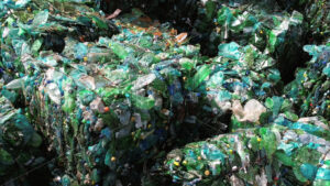 Multiple cubes of compressed green plastic garbage at waste recycling factory in open air - Starpik
