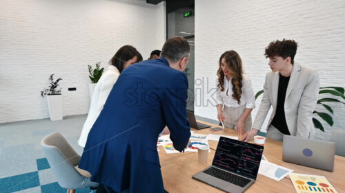 Multiracial group of people at business meeting in an office, discussing business affairs with each other using papers and gadgets on the table - Starpik