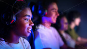 Premium stock video footage – White boy and black girl teens in headsets playing video games in video game club with blue and red illumination. Slow motion - Starpik Stock