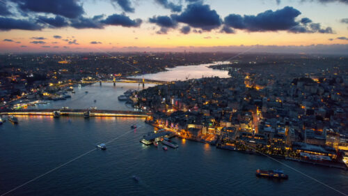 Video – Aerial drone view of Istanbul at sunset, Turkey. Multiple residential buildings, mosques, Galata and Metro bridges over the Golden Horn waterway with multiple floating ships, nightlights - Starpik Stock
