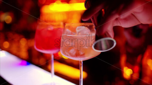 Video – Barman making a cocktail with bitter alcohol at the bar at night with red neon lights, slow motion - Starpik Stock