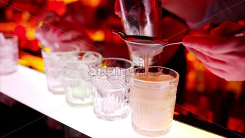 Video – Barman making cocktails with whiskey liquor alcohol at the bar at night with red neon lights, slow motion - Starpik Stock