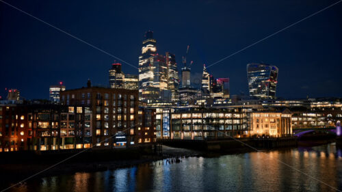 Video – Cityscape of London downtown at night, United Kingdom. Skyscrapers in City district and other buildings, Thames River, a lot of illumination - Starpik Stock