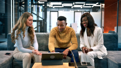 Video – Multiracial group of people in an office discussing business while sitting on a sofa, tablet on the table - Starpik Stock