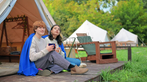 A couple talking and entering a tent at glamping. Lush forest around - Starpik Stock