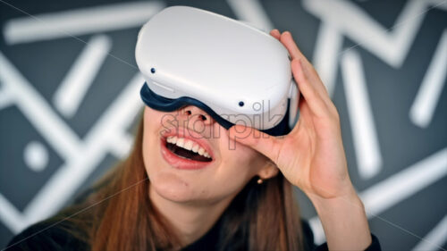 A young woman in VR glasses is excited while playing VR games. Slow motion - Starpik Stock