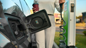 A young woman takes a charger at a car charging station and inserts it into electric car. Chisinau, Moldova - Starpik