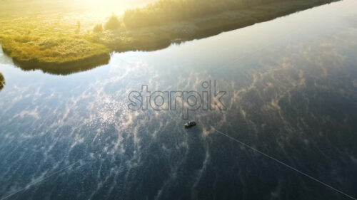 Aerial cinematic drone view of a man in a boat fishing on Nistru river at sunrise. Fog on the water in Moldova - Starpik Stock