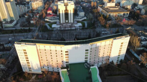 Aerial drone cinematic view of Chisinau at sunset. Panorama view of the Presidency and Parliament, multiple buildings in city center, roads with moving cars, bare trees. Moldova - Starpik Stock