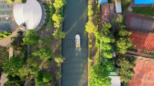 Aerial drone view of Bega river in Timisoara, Romania. View of the river with floating boat, greenery and buildings on the both sides of the river - Starpik Stock