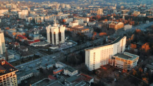 Aerial drone view of Chisinau at sunset. Panorama view of the Presidency and Parliament, multiple buildings in city center, roads with moving cars, bare trees. Moldova - Starpik Stock