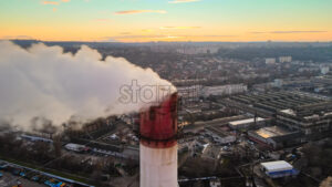 Aerial drone view of Chisinau at sunset. Tube of the thermal station with smoke coming out. Industrial zone near it and cityscape on the background. Moldova - Starpik Stock