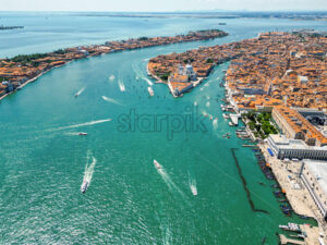 Aerial drone view of Venice, Italy. Water channels with multiple floating and moored boats, historical city centre with Santa Maria della Salute and other old buildings and narrow streets - Starpik Stock