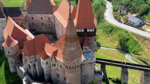 Aerial drone view of the Corvin Castle located in Hunedoara, Romania. Bridge leading to the entrance. Greenery and buildings around - Starpik Stock