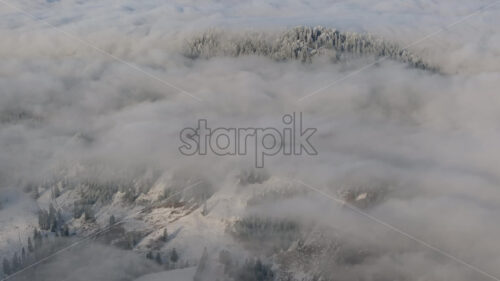 Aerial drone view of winter mountains with fog in Ceahlau National Park, Romania - Starpik Stock