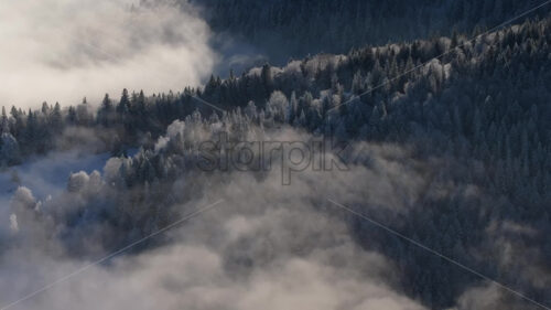 Aerial drone view of winter mountains with fog in Ceahlau National Park, Romania - Starpik Stock