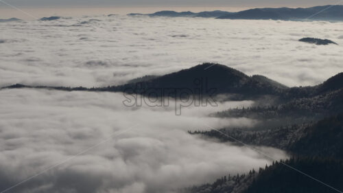 Aerial drone view of winter mountains with fog in Ceahlau National Park, Romania - Starpik Stock