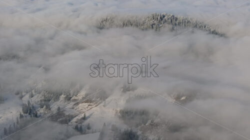 Aerial drone view of winter mountains with fog in Ceahlau National Park, Romania - Starpik Stock