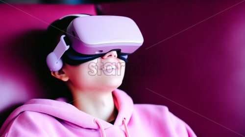 American woman enjoying what she sees in her virtual reality goggles in their entertainment room in pink colors - Starpik Stock