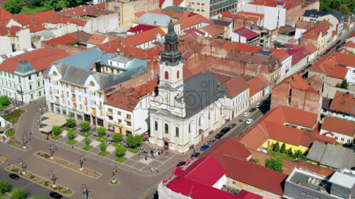 Areal drone view of the Moon Church in Oradea downtown, Romania. Historical buildings and walking people around - Starpik Stock