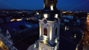 Areal drone view of the Moon Church in Oradea downtown at night, Romania. Historical buildings and cars with illumination around - Starpik Stock