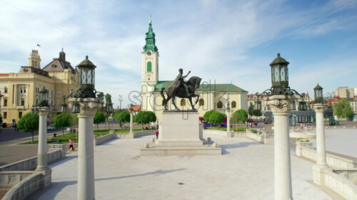 Areal drone view of the Unirii Square in Oradea downtown, Romania. King Ferdinand I statue, Saint Ladislaus Church and Town Hall, walking people - Starpik Stock