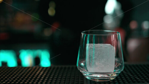 Bartender adding big ice cube into an alcoholic cocktail glass - Starpik Stock