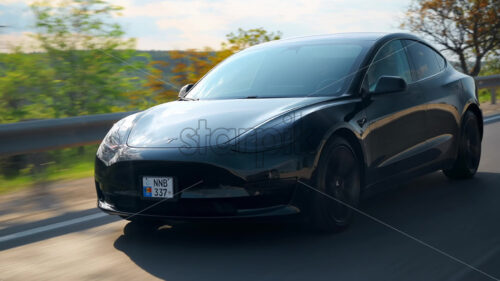 CHISINAU, MOLDOVA – MAY, 2023: Front view of a moving black Tesla Model 3 on a highway. Nature on the background - Starpik Stock