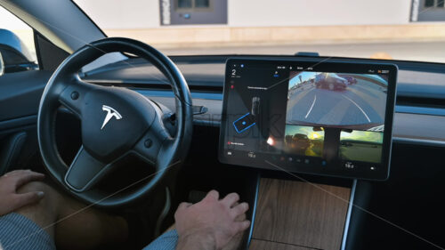 CHISINAU, MOLDOVA – MAY, 2023: Interior view of a Tesla Model 3 parking on autopilot. Driver not touching the steering wheel - Starpik Stock