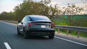 CHISINAU, MOLDOVA – MAY, 2023: Rear view of a moving black Tesla Model 3 on a highway. Nature on the background. Slow motion - Starpik Stock