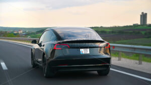 CHISINAU, MOLDOVA – MAY, 2023: Rear view of a moving black Tesla Model 3 on a highway. Nature on the background. Slow motion - Starpik Stock