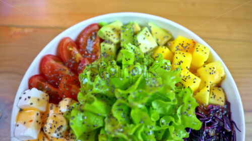 Close up poke bowl with salmon fish, avocado, feta cheese, mango, tomatoes, salad, and green edamame beans - Starpik Stock