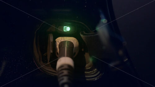 Close view of a charger plugged into an electric car at night - Starpik
